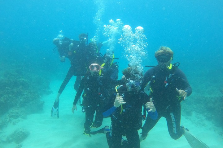 Group of scuba divers underwater posing with bubbles.