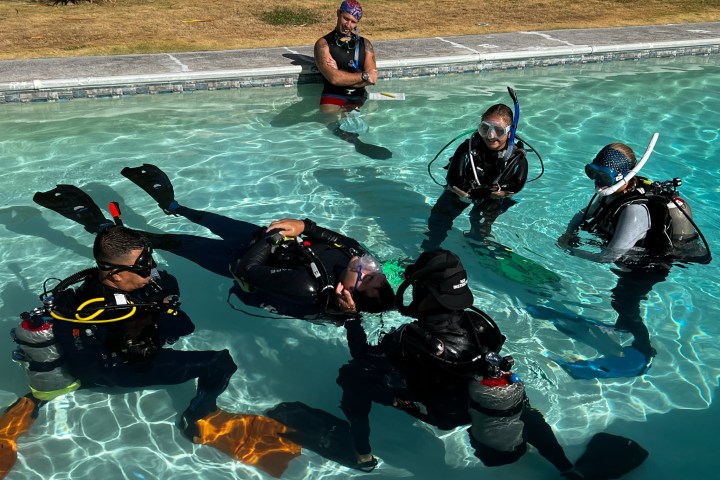 Group of scuba divers practicing rescue techniques in a pool.
