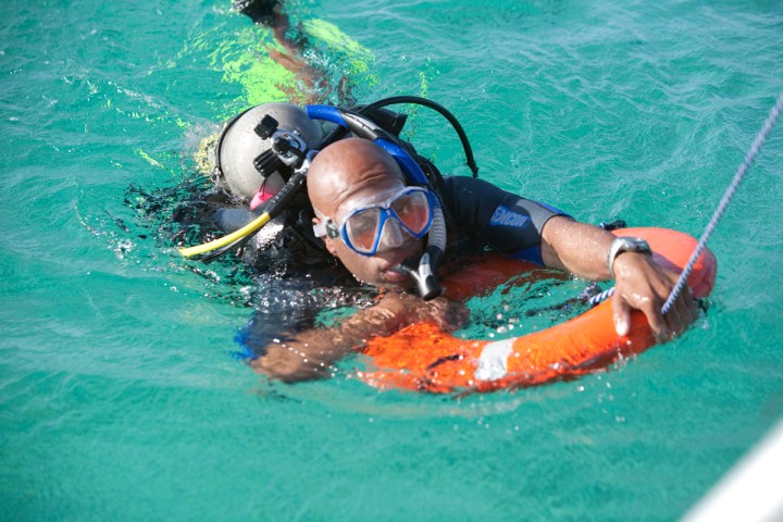 Scuba diver in water holding an orange lifebuoy.