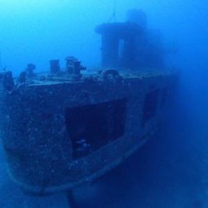 Underwater view of a sunken ship covered in marine life.