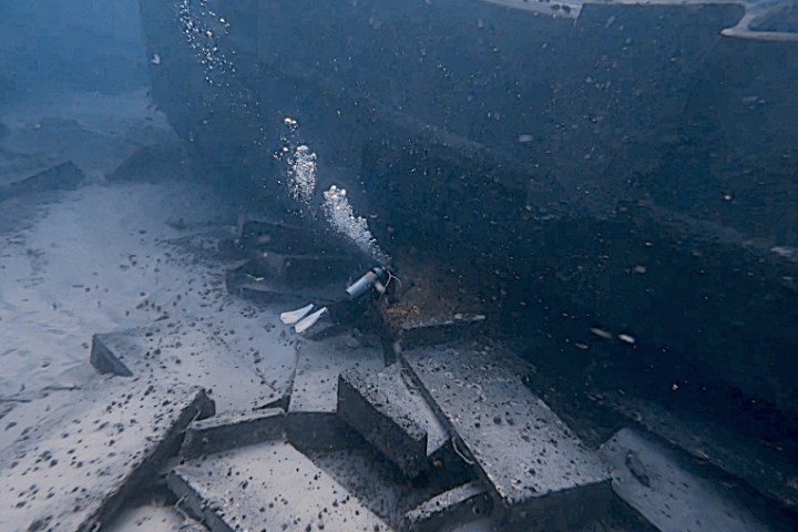 Scuba diver exploring a sunken shipwreck underwater.